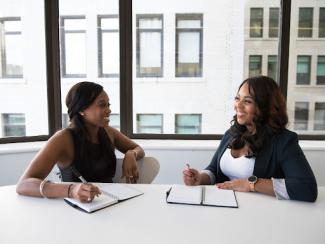 Two women sitting at table speaking with each other
