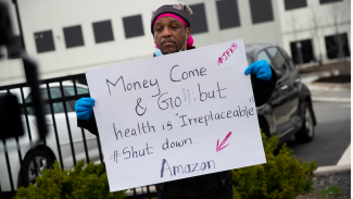 Man holding protest sign against Amazon corporation
