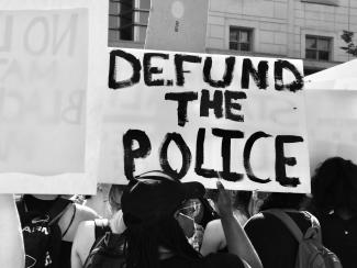 Demonstrators holding "Defund The Police" sign