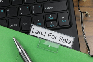 Folder labeled "Land For Sale" on top of computer keyboard