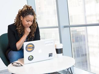 black woman sitting down in front of a laptop 