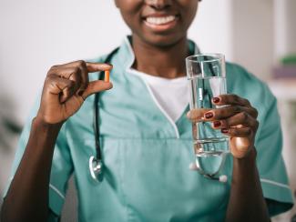 Doctor holding pill and glass of water