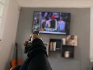Person pointing remote at TV