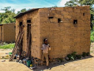 Young boy in front of a small home