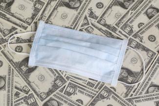 Medical face mask on a pile of money