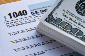 US tax form 1040 and stack of cash