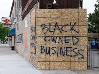 "Black Owned Business" spray painted on boarded up building