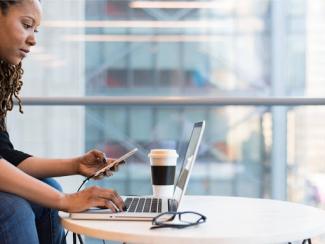 woman checking her phone while being on the laptop