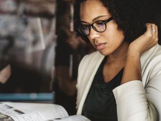Woman in glasses reads magazine