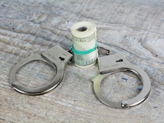 handcuffs with a roll of money in between the cuffs