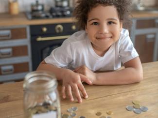 curly haired kid in a white shirt counting coins on a counter