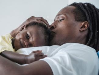 black mother holding her child close to her chest 