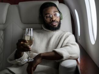 black holding glass of champagne in an airplanev