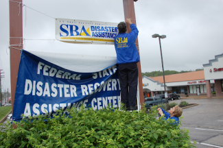 person putting up sba disaster recovery assistance center sign