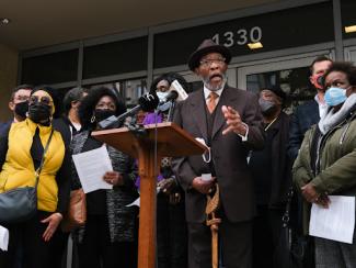 black people crowded around a podium at a rally