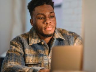 thoughtful black guy browsing laptop in room