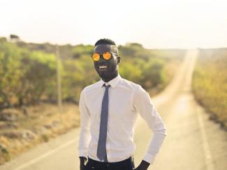 happy black man in formal wear and glasses in countryside