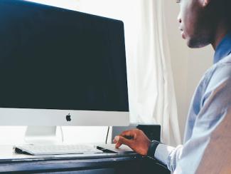 black man sitting in front of a desktop computer