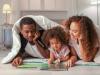 Family reading book on bedroom floor