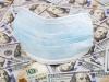 Medical face mask on the top of hundreds of US dollar bank notes