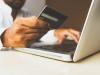 Someone holding credit card in front of laptop