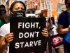 Protester holding up a sign that reads Fight Don't Starve 