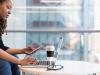 woman checking her phone while being on the laptop