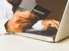 person holding a credit card while typing on a laptop