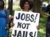 black woman holding a sign that says jobs not jails