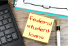 yellow stick notepad that has federal student loans written on it