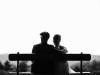 two people sitting together on a bench outside