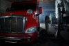 curly hair woman wearing brown long sleeve playsuit standing red and silver truck