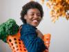 happy young black woman holding basket with lettuce on shoulder