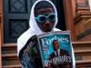 black man holding a forbes magazine outside