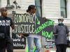people protesting holding up signs saying economic justice and reparation now 