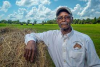 black farmer next to a bale of hay