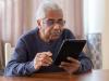 elderly man in black sweater using a digital tablet